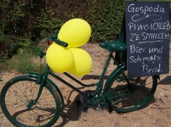 Rower z żółtymi balonami i tablicą przy gospodzie.